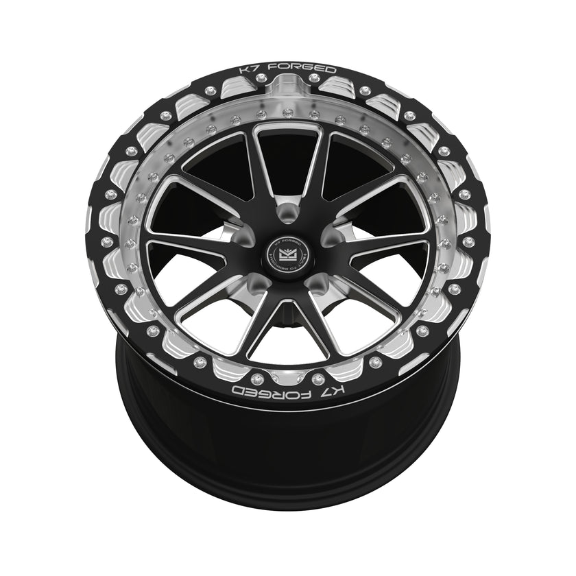 K7 Forged DRG-717B — B-series beadlock-style black outer ring with scalloped silver accents and split V-spoke black face — front face hero
