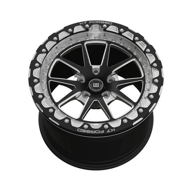 K7 Forged DRG-717B — B-series beadlock-style black outer ring with scalloped silver accents and split V-spoke black face — front face hero